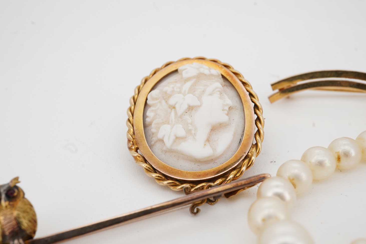 A 9ct owl bar brooch, with cabochon eyes, 50mm, a 1960's 9ct gold and amethyst set bar brooch, an 18ct and amethyst set bar brooch, a cameo brooch(a.f.) and a cultured pearl necklace with 9ct gold clasp.
